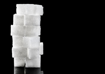 Stack of sugar cubes on black. Space for text.