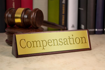 Golden sign with gavel and law books and compensation on a desk