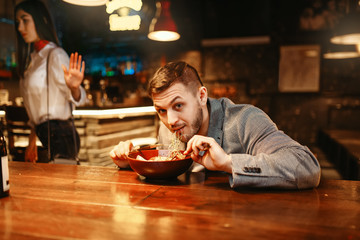 Couple in quarrel, man eats at bar counter