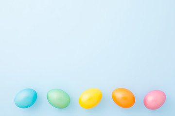 Colorful shiny Easter eggs on a spring light blue background. Flat lay. Top view. Copy space