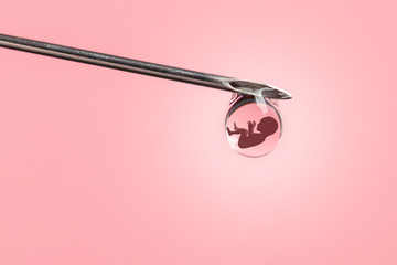 Artificial insemination. Test tube baby, IVF. On the tip of the needle drop of syringe with the silhouette of baby embryo.