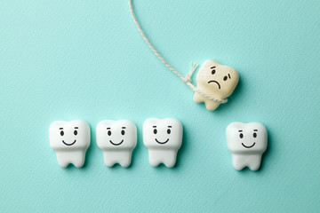 Healthy white teeth are smiling and the removal of the baby tooth with rope is sad on green mint background. Toothbrush and dentist tools mirror, hook.