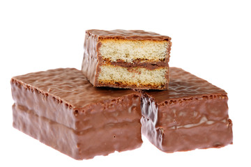 Close up of two and a half sliced sponge cake bars with cocoa cream center, topped with milk chocolate. Isolated on white background