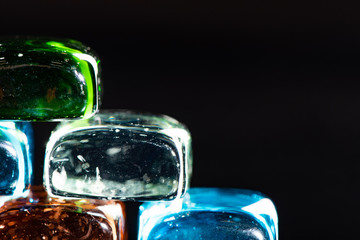 Macro photo of glass cubes of different colors on a black background with reflections