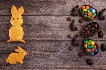 Flat lay composition with Chocolate Easter eggs, rabbit and sweets on dark wooden background. Top view. With copy space