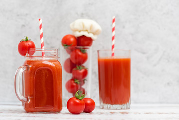 Fresh tomato juice in glasses and cherry tomatoes on light background
