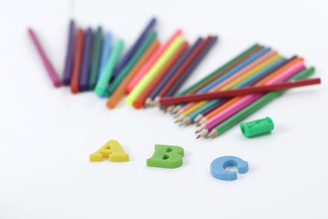 colored pencils and letters of the alphabet on a white background .photo with copy space