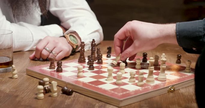 Man gets a checkmate during a chess game. Parallax shot of male hands playing a chess game and one loses.