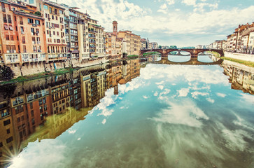 Buildings and Ponte Santa Trinita mirrored in river Arno, Florence, Italy - obrazy, fototapety, plakaty