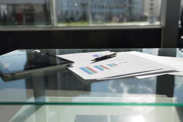 digital tablet, financial chart and pen on the coffee table