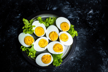 Fototapeta na wymiar plate with hard-boiled eggs and green leaves of lettuce