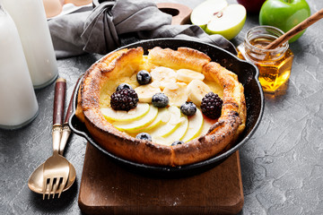 Dutch baby pancake with apples, banana, fresh berries powdered sugar and almonds.
