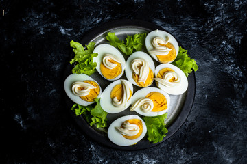 plate with hard-boiled eggs, with the addition of mayonnaise and green leaves of lettuce