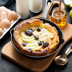 Dutch baby pancake with apples, banana, fresh berries powdered sugar and almonds.