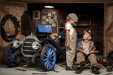 Obraz na płótnie Canvas Boys-mechanic with tools in the car in the garage