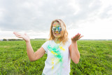 Fun, happy, people and holidays concept - Young cheerful woman at Holi paint party