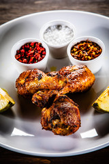 Grilled chicken drumsticks with pear on wooden background