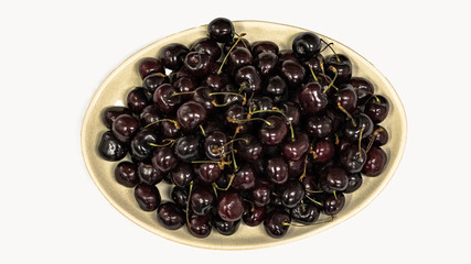 Top view of cherries in a plate on a white background