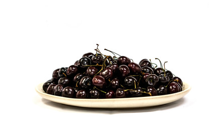 Top view of cherries in a plate on a white background