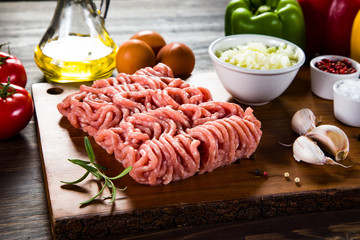 Raw minced pork on cutting board and vegetables