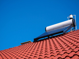 Solar water heater boiler on rooftop, perfect blue sky  on the background. © Alpar