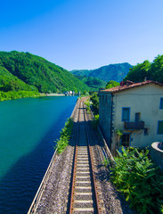 Railway that runs along the blue lake in the green mountains