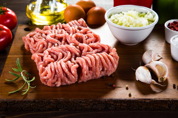 Raw minced pork on cutting board and vegetables