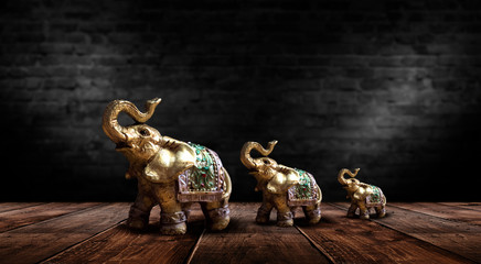 Golden elephant on a wooden table. Dark room, light effect. Beautiful statuette of an elephant on the background.