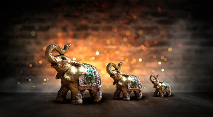 Golden elephant on a wooden table. Dark room, light effect. Beautiful statuette of an elephant on...