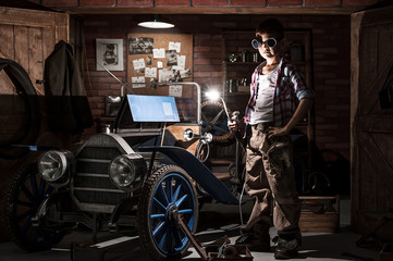 Obraz na płótnie Canvas Young mechanic with a welder at the car in the garage