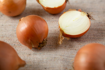 Obraz na płótnie Canvas Unpeeled raw yellow onions on cloth, low angle view. Close-up.