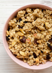 From above, pink bowl of fruit granola over white wooden surface. Top view, overhead, flat lay.