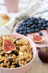 Pink bowl of fruit granola with fruits and honey, low angle view. Closeup.