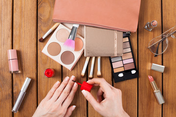 Makeup products with woman doing nail polish