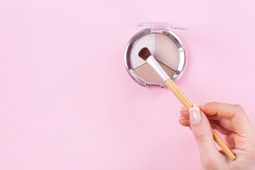 Hand holding brush and eyeshadow