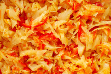 Texture of vegetable cabbage stew. View from above. White cabbage, carrots, tomatoes, onions, sweet peppers, garlic in a vegetable stew recipe. Vegetable stew for diet.