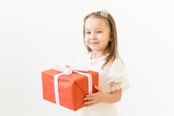Childhood, children and holiday concept - little girl in white dress with gift box on white background