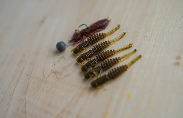 Colorful silicone fishing baits with plummets on wooden table. Various fish and worms and crayfish. Toned image and top view. Stock background, photo