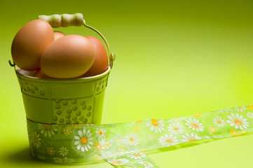 Raw Easter eggs in green bucket and ribbon with copy space 