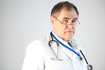 The doctor looks forward, pushing his glasses to the tip of his nose, a stethoscope and a badge hanging from his neck