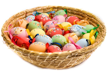 Colorful Easter eggs decorated and with ribbons in basket over white isolated background 