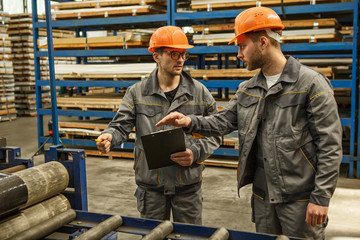 Two industrial workers checking stock with a clipboard
