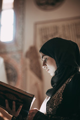 Young muslim girl reading a holy book