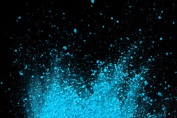 Blue color background of chalk powder. Blue color dust particles splattered on black background.