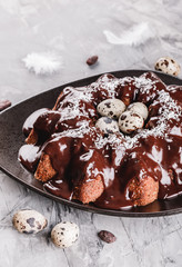 Easter cake with chocolate, coconut, spring flowers, quail eggs on a stone background. Happy Easter celebration
