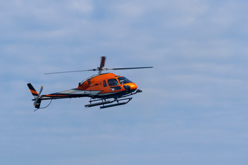 Fototapeta na wymiar Fliegender Helikopter vor blauem Himmel mit Wolken