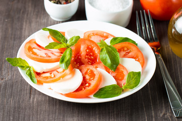 Close-up photo of caprese salad with ripe tomatoes, basil, buffalo mozzarella cheese. Italian and Mediterranean food concept. Fresh and healthy organic meal. Starter and antipasti. 