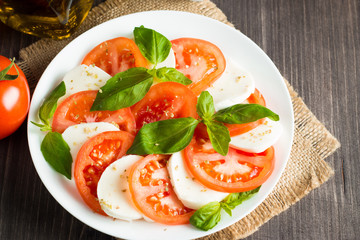Close-up photo of caprese salad with ripe tomatoes, basil, buffalo mozzarella cheese. Italian and Mediterranean food concept. Fresh and healthy organic meal. Starter and antipasti. 