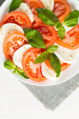 Close-up photo of caprese salad with ripe tomatoes, basil, buffalo mozzarella cheese. Italian and Mediterranean food concept. Fresh and healthy organic meal. Starter and antipasti. 