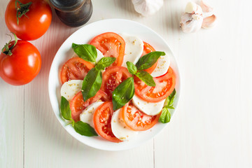 Close-up photo of caprese salad with ripe tomatoes, basil, buffalo mozzarella cheese. Italian and Mediterranean food concept. Fresh and healthy organic meal. Starter and antipasti. 